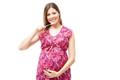 smiling pregnant woman brushes teeth